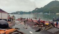People stand on the roofing of collapsed shops in the port after a 5.1-magnitude earthquake in Jayapura, Indonesia's eastern province of Papua on February 9, 2023. (Photo by FAISAL NARWAWAN / AFP)