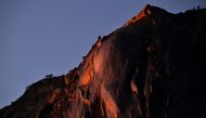 Water flowing off Horsetail Fall glows orange while backlit from the setting sun during the 