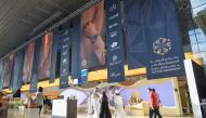 Individuals walking near Doha Jewellery and Watches Exhibition at the DECC. 