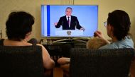 A family watches a TV broadcast of Russian President Vladimir Putin's annual state of the nation address in Moscow on February 21, 2023. (Photo by Yuri Kadobnov/ AFP)
 