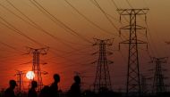 File Photo: Locals walk past electricity pylons during frequent power outages from South African utility Eskom, caused by its aging coal-fired plants, in Orlando, Soweto, South Africa, on September 28, 2022. Reuters

