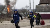 Journalists run for cover after heavy shelling in Irpin, near Kyiv. REUTERS/Carlos Barria