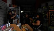 A woman buys water at shop in the dark in Buenos Aires on March 1st, 2023, following an outage caused by a fire which affected the high-voltage system.  (Photo by Luis ROBAYO / AFP)