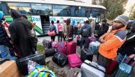 Sub-Saharan migrants queue to board a bus with their belongings as they head to a repatriation flight, leaving Tunis for their countries of origin on March 4, 2023. (Photo by Fethi Belaid / AFP)
 