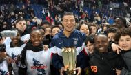 Paris Saint-Germain's French forward Kylian Mbappe poses with a trophy and children at the end of a ceremony after he became Paris Saint-Germain's all-time top scorer on March 4, 2023. (Photo by Franck Fife / AFP)