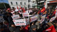 Demonstrators lift placards during an anti-government demostration called for by the powerful trades union federation UGTT in Tunis, on March 4, 2023. (Photo by FETHI BELAID / AFP)

