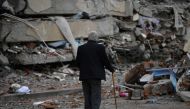 A man walks among debris of collapsed buildings in Kahramanmaras, on March 4, 2023, one month after a massive earthquake struck south-east Turkiye.  (Photo by Eylul Yasar / AFP)
