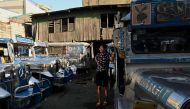 A woman stands beside a parked jeepneys in Quezon City on March 6, 2023. Photo by JAM STA ROSA / AFP