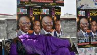 A woman lies beside campaign posters of Lagos gubernatorial candidate of the ruling All Progressives Congress (APC) Babajide Sanwo-Olu and runningmate Obafemi Hamzat displayed at a bus station in Lagos, on March 7, 2023 ahead of March 11 gubernatorial elections.  (Photo by PIUS UTOMI EKPEI / AFP)