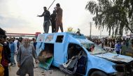 Pakistan's former Prime Minister Imran Khan's supporters stand atop a damaged police van outside a court in Islamabad on March 18, 2023. (Photo by Farooq NAEEM / AFP)