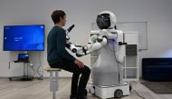 An employee sits in front of the robot Garmi in the laboratory of the Research Center Geriatronics of the Technical University Munich, in Garmisch-Partenkirchen, southern Germany, on March 6, 2023. (Photo by Christof Stache / AFP)