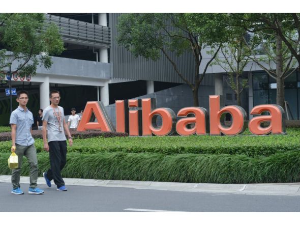 This file photo taken on May 27, 2022 shows staff members walking past the logo of Chinese e-commerce giant Alibaba at its headquarters in Hangzhou, in China's eastern Zhejiang province. Photo by AFP