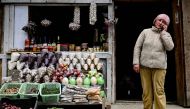 A shopkeeper speaks on her phone as she waits for customers at her shop along a road in India's north-eastern state, Arunachal Pradesh on April 2, 2023. (Photo by Arun Sankar / AFP)