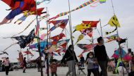 People walk past vendors selling kites at Hsinchu fishing port on April 9, 2023. (Photo by Jameson Wu / AFP)