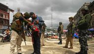 An Indian security personnel searches the bag of a pedestrian during a random search in Srinagar on April 20, 2023. (Photo by Tauseef Mustafa / AFP)