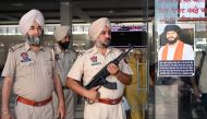 Punjab police stand guard beside Amritpal Singh's poster at a railway station in Amritsar on April 23, 2023. Photo by Narinder NANU / AFP)
