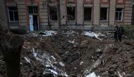 Teenagers stand next a crater left by a missile strike in front of a school building in Kramatorsk, in the Donetsk region on April 24, 2023, amid the Russian invasion of Ukraine. Photo by Anatolii STEPANOV / AFP