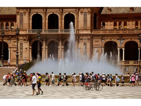 A group of schoolchildren on a excursion cool off walking along a fountain at the Plaza Espana square in Seville on April 26, 2023 as Spain is bracing for an early heat wave. Photo by CRISTINA QUICLER / AFP