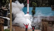 Opposition supporters react after a teargas canister was shot by Kenyan police officers during riots in the informal settlement of Kibera in Nairobi on May 2, 2023. (Photo by Luis Tato / AFP)