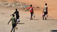 Youths carry buckets of water in the Sudanese capital Khartoum, on May 4, 2023. Photo by AFP