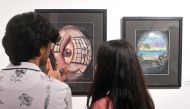 Visitors look at the paintings made by Ahmed Rabbani, during an exhibition of his work, in Karachi. (Photo by Rizwan Tabassum / AFP) 