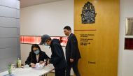A worker (L) at the Consulate General of Canada tends to a man at the entrance of the consulate in Shanghai on May 9, 2023. (Photo by Hector Retamal / AFP)