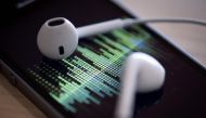 A picture taken on February 8, 2019 in Paris shows a smartphone and its earphones as an audio podcast is being played. Photo by Thomas SAMSON / AFP
