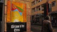 A man waits to cross the road beside a patriotic poster in Asmara, Eritrea, on July 18, 2013. Parties, music and dancing lasted the entire month to commemorate Eritrea's liberation from Ethiopian rule in May 1991, and its overwhelming support for independence in a UN-backed referendum two years later. (Photo by Jenny VAUGHAN / AFP)
