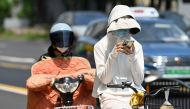 A woman wearing sun protective clothing commutes on a bicycle amid hot weather in Shanghai on May 29, 2023. Photo by AFP