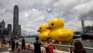 People take photos of two large inflatable yellow ducks called 