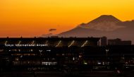 A general view shows the terminal building of Haneda Airport with Mount Fuji (back-R) from the airport's observation deck in Tokyo on February 28, 2023. (Photo by Philip FONG / AFP)