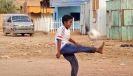 A child plays with a football along a street in Khartoum on June 14, 2023. (Photo by AFP)