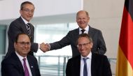 Pat Gelsinger (background left), CEO of US multinational corporation and technology company Intel, and German Chancellor Olaf Scholz (background right) shake hands after State Secretary at the Chancellery Joerg Kukies (foreground right) and Intel Executive Vice President Keyvan Esfarjani signed an agreement between the German government and Intel on June 19, 2023 at the Chancellery in Berlin. (Photo by Odd Andersen / AFP)