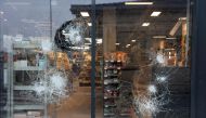 An employee is seen behind the broken windows of a supermarket following a fourth consecutive night of rioting in France sparked by the death of teenage driver Nahel by a police bullet, in Talence, south-western France on July 1, 2023. (Photo by ROMAIN PERROCHEAU / AFP)

