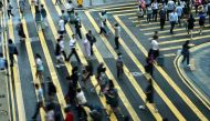 People cross a road in Central, a financial hub in Hong Kong on July 3, 2023. (Photo by May James / AFP)