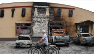 An elderly man riding a bicycle pushes the bike of his wife killed by a cluster bomb in Lyman, Donetsk region, on July 8, 2023. (Photo by STRINGER / AFP)
