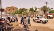 Pedestrians and vehicles move along a road outside a branch of the Central Bank of Sudan in the country's eastern city of Gedaref on July 9, 2023. (Photo by AFP)