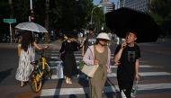 People shelter under umbrellas during heatwave conditions in Beijing on July 19, 2023. (Photo by Greg Baker / AFP)