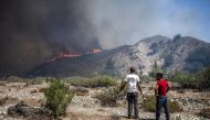 Locals watch the wildfires near the village of Vati, just north of the coastal town Gennadi, in the southern part of the Greek island of Rhodes on July 25, 2023. Photo by Angelos Tzortzinis / AFP