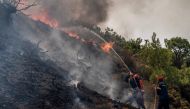 Firefighters use a hose as they take part in an operation against a fire near Vati, on the Greek Aegean island of Rhodes on July 26, 2023. Photo by Angelos Tzortzinis / AFP