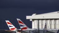 Sunlight illuminates the tailfins of British Airways aircraft at Terminal 5 of London Heathrow Airport in west London (Photo by Adrian DENNIS / AFP)