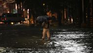 This photo taken July 29, 2023 shows a pedestrian wading a flooded street of Manila as Tropical Storm Khanun intensifies the southwest monsoon rain. (Photo by Ted Aljibe / AFP)
