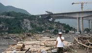 A man stands on a broken bridge at a flood-affected area following heavy rains in Beijing on August 3, 2023. Photo by Jade Gao / AFP