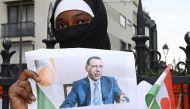 A woman holds the image of ousted Niger President Mohamed Bazoum, 63, who has been held by coup plotters with his family in his official Niamey residence since July 26, during a protest outside the Niger Embassy, in Paris on August 5, 2023. (Photo by Stefano Rellandini / AFP)
