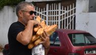 A man carries baguettes bought from a bakery in Tunis on August 7, 2023. (Photo by FETHI BELAID / AFP)
