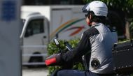 This photo taken on August 4, 2023 shows a man wearing a jacket with battery-powered built-in fans to keep cool in the heat as he sits on his motor scooter along a street in Tokyo. (Photo by Richard A. Brooks / AFP) 