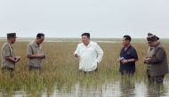 This picture taken on August 21, 2023 and released from North Korea's official Korean Central News Agency (KCNA) on August 22, 2023 shows North Korea's leader Kim Jong-un (centre) in waste-deep water as he visits the restoration site of reclaimed land which suffered flood damage due to the levee breaking in the western port city of Nampo. (Photo by KCNA VIA KNS / AFP)