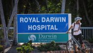 A woman rides a bicycle near the entrance to Royal Darwin Hospital in Darwin on August 28, 2023, as investigations continue after three US Marines died on August 27 when an Osprey aircraft crashed on Melville Island, located north of Darwin. (Photo by DAVID GRAY / AFP)