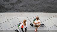 A couple uses battery-powered electric scooters from a sharing company on the banks of the river Spree in Berlin on August 27, 2023. (Photo by John MacDougall / AFP)
 