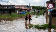People wade through the water in a flooded area of Batabano, Mayabeque Province, Cuba, on August 28, 2023, as Tropical Storm Idalia approaches the western tip of the island nation. Photo by Yamil LAGE / AFP